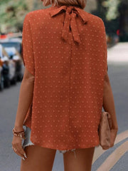 Textured dot back-tie blouse in caramel with short sleeves and a bow detail at the neck.