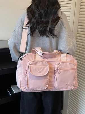 Pink nylon duffle bag with multiple front pockets and adjustable strap.