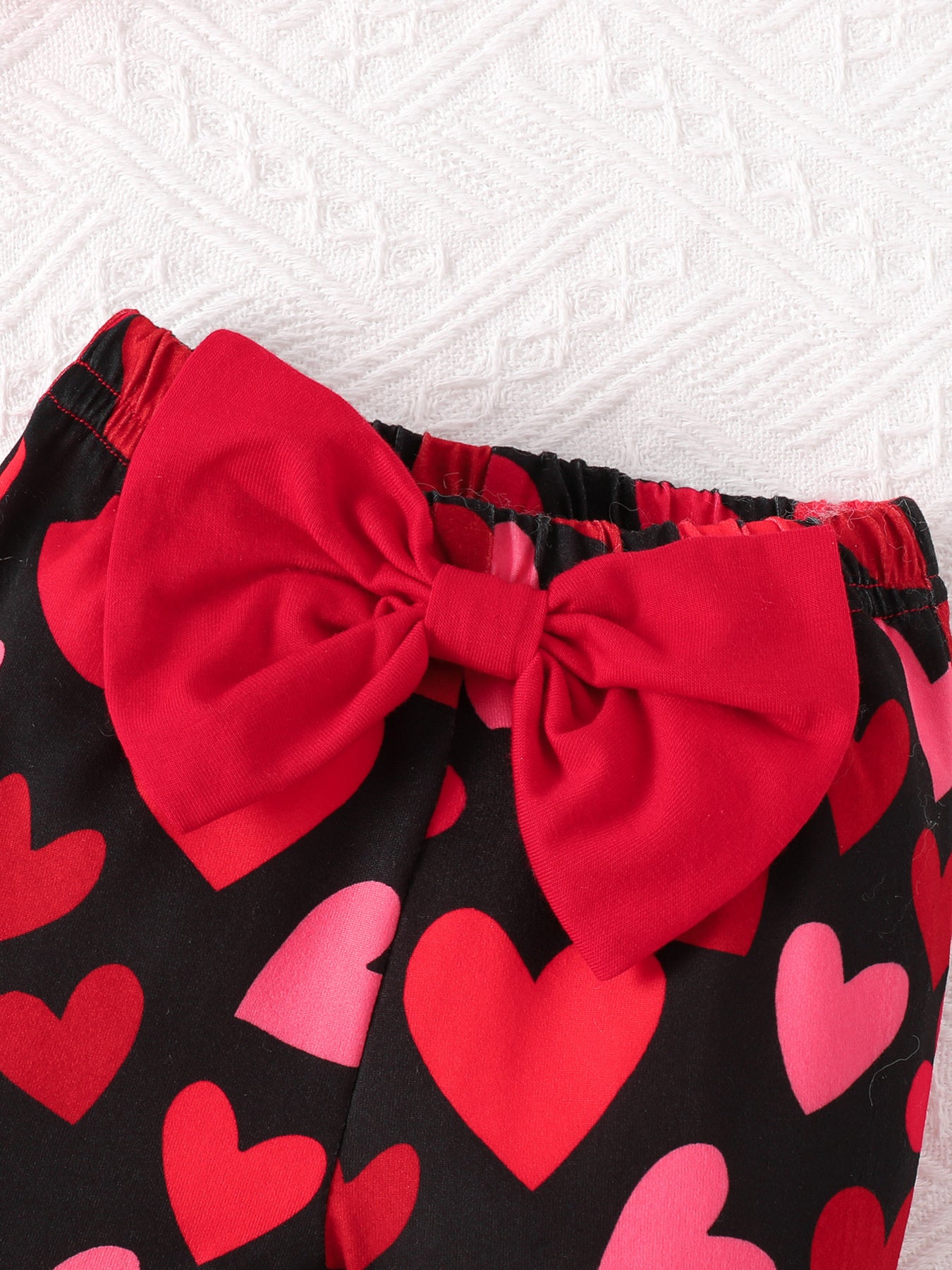 Baby bell-bottoms with black heart print and red bow detail.