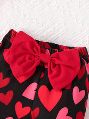 Baby bell-bottoms with black heart print and red bow detail.