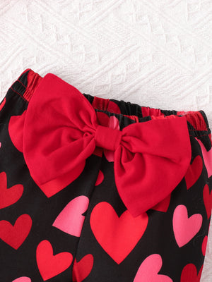 Baby bell-bottoms with black heart print and red bow detail.