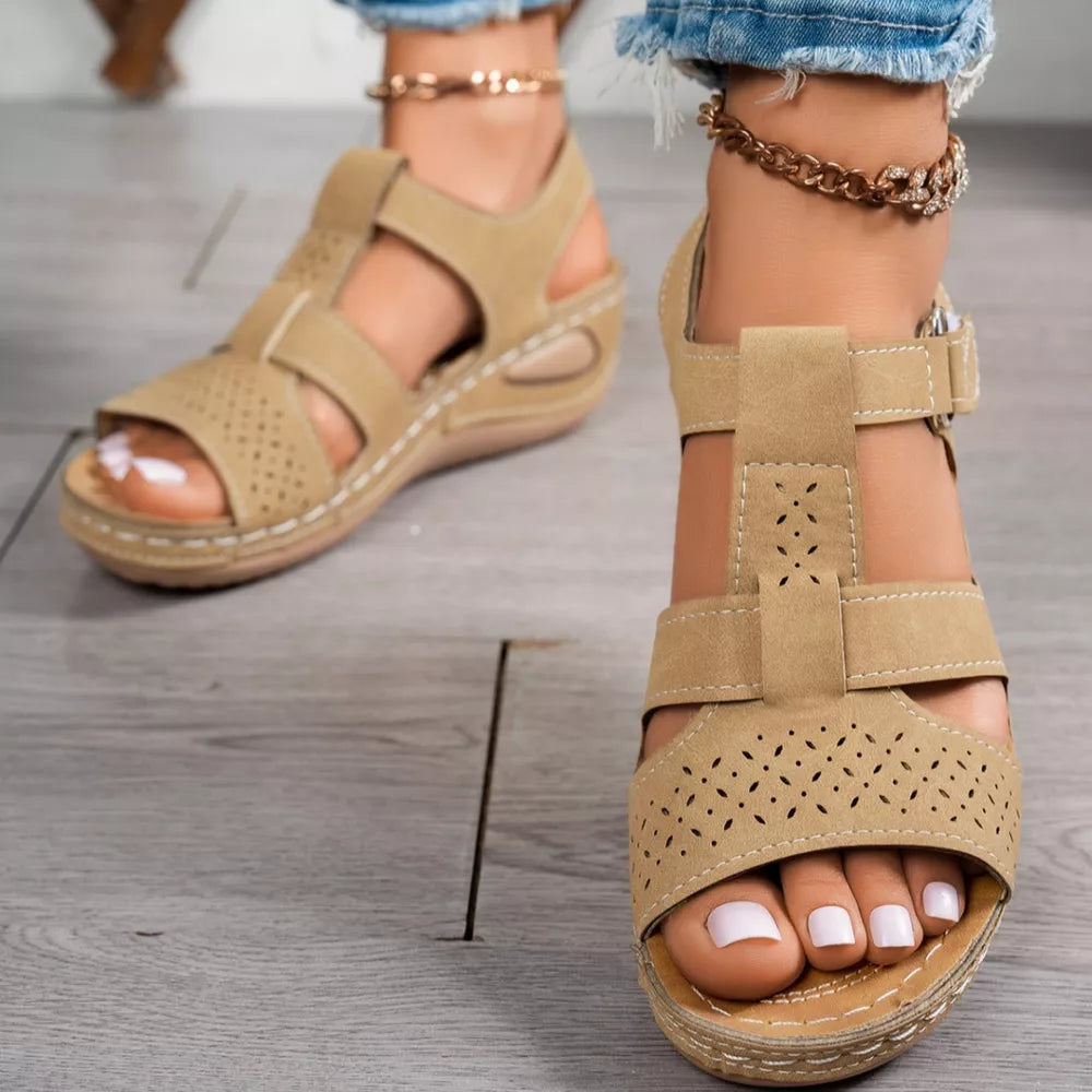 Elegant perforated tan mid-wedge sandals with adjustable strap and breathable cutouts.