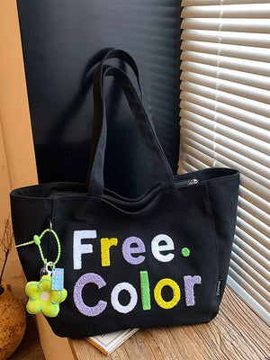 Black canvas shoulder bag with embroidered "Free. Color" text and flower charm.