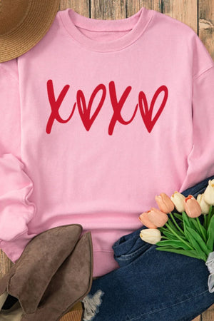 Blush pink relaxed fit sweatshirt with red XOXO graphic print.