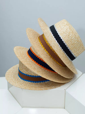 Straw boater hats stacked with decorative bands in blue, orange-red, and navy.
