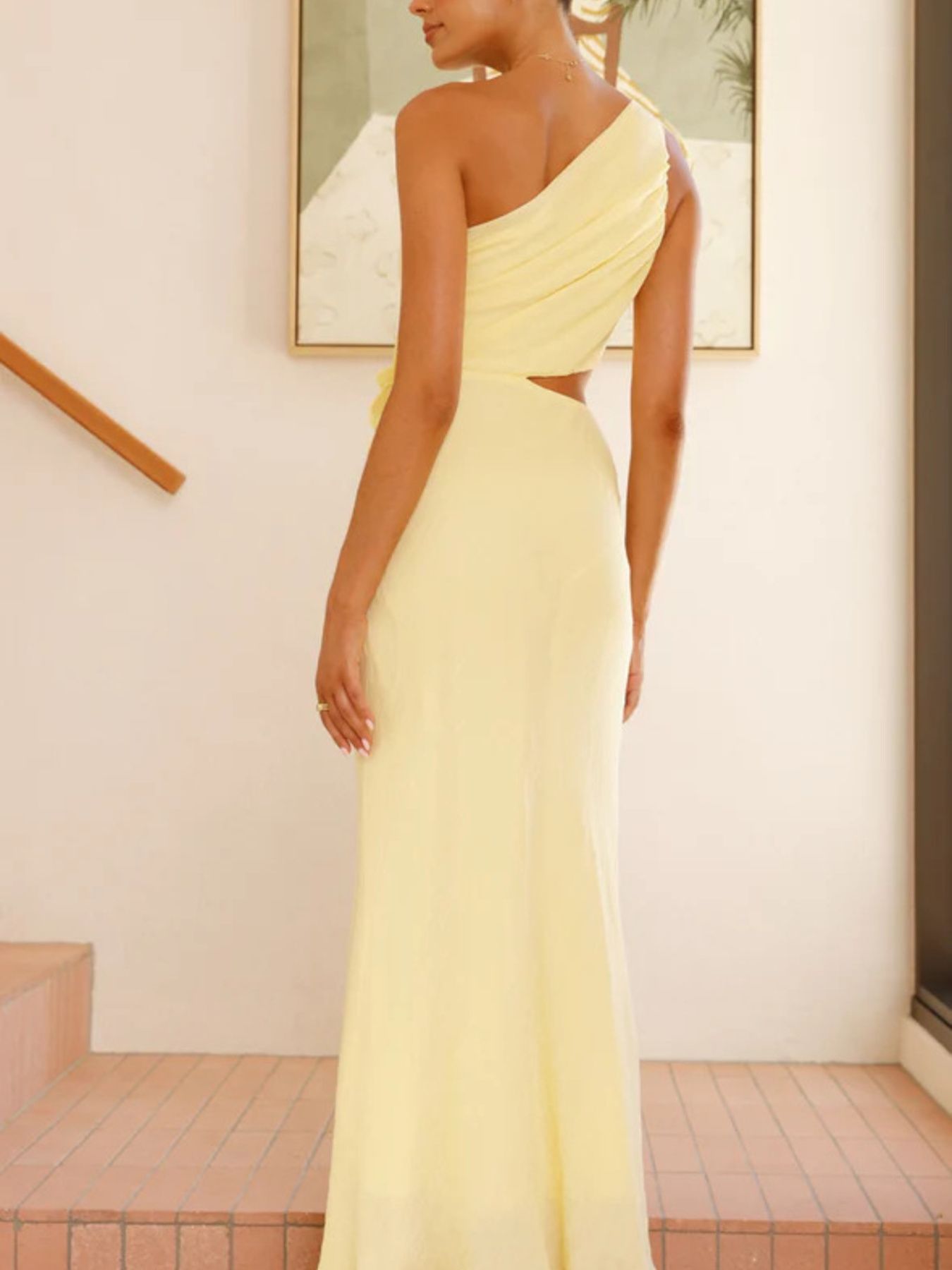 Yellow one-shoulder maxi dress with cutout detail and floral appliqué.
