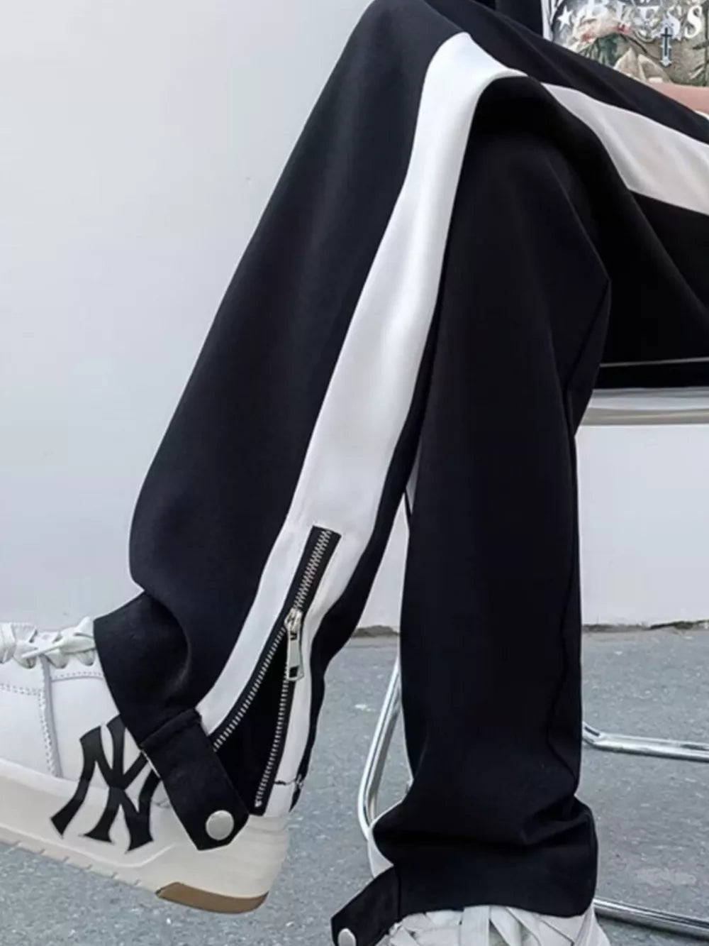 Black sweatpants with white side stripe and ankle zipper detail.