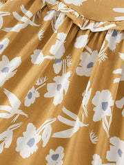 Toddler dress with white floral and bird print on mustard cotton blend, featuring a ruffled neckline.