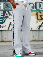 Light gray sweatpants with wide legs and side snaps, featuring a black bandana print stripe.