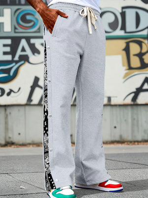 Light gray sweatpants with wide legs and side snaps, featuring a black bandana print stripe.