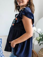 Navy embroidered floral blouse with ruffle sleeves and a babydoll cut.