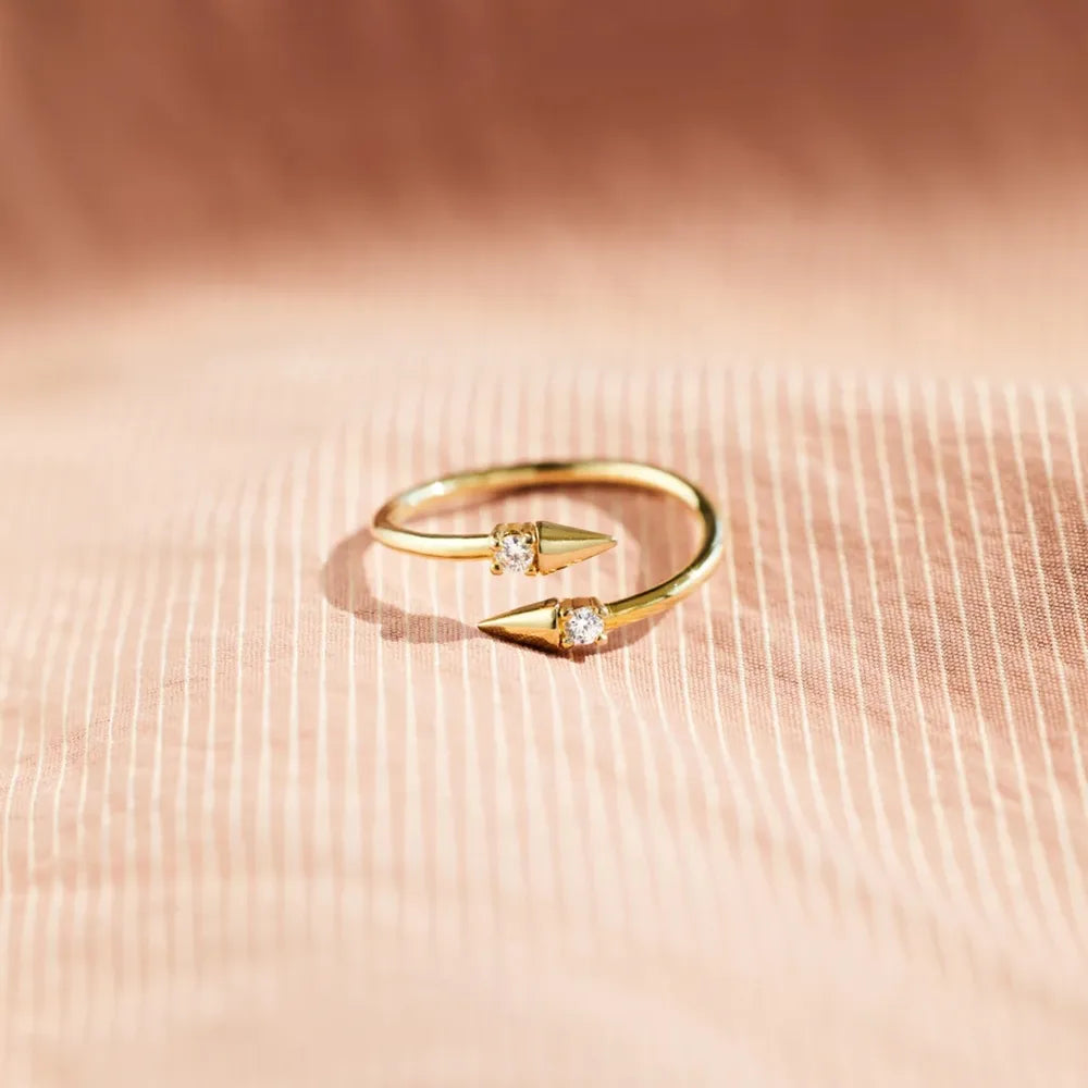Gold bypass ring with two spiked ends, each set with a clear zirconia stone.