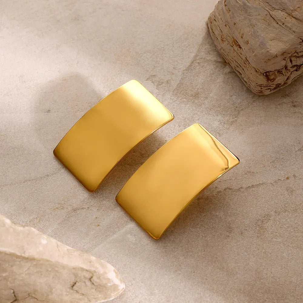 Sculpted gold-tone statement earrings with a bold, curved design.