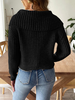 Black ribbed knit sweater with a wide shawl collar and long sleeves.