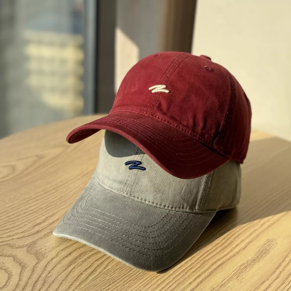 Distressed cotton baseball hats in Wine Red and Dark Gray with embroidered logos.