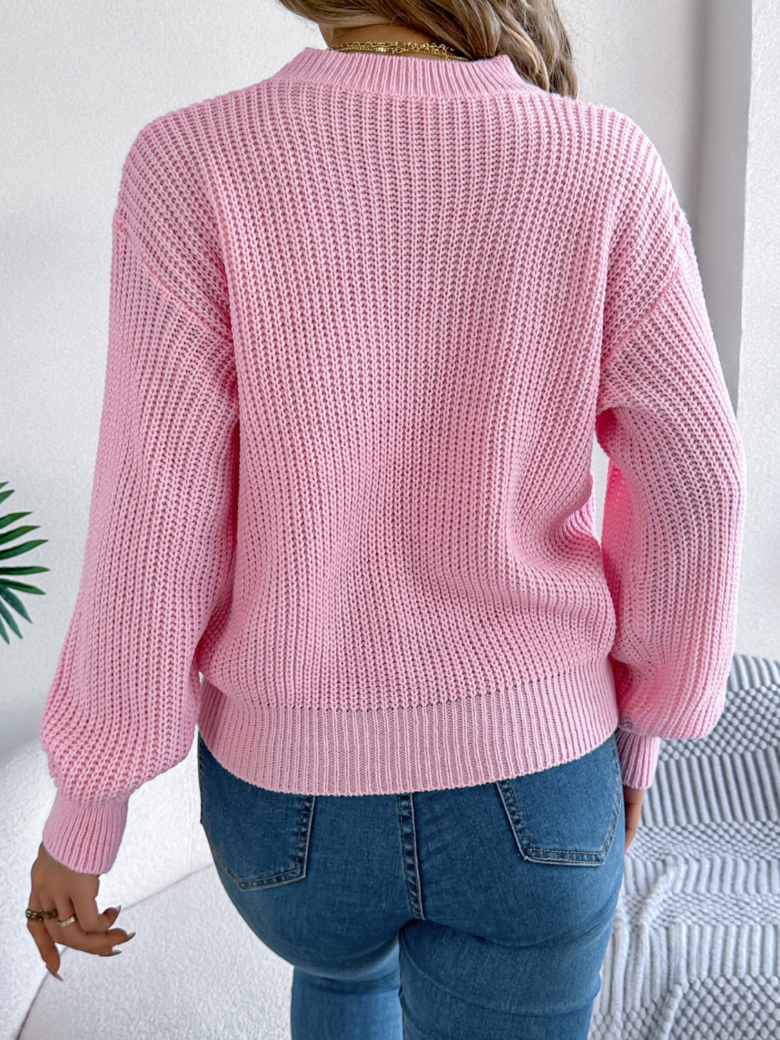 Blush pink acrylic knit sweater with ribbed texture and balloon sleeves.