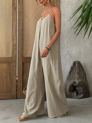 Sleeveless frill-trimmed beige jumpsuit with wide legs and spaghetti straps.