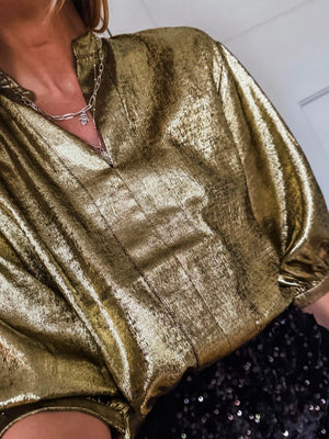 Gold crinkled blouse with notched V-neck and 3/4 sleeves, styled with a silver necklace.