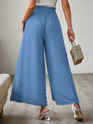 Blue paperbag waist palazzo pants with side slits and textured fabric.