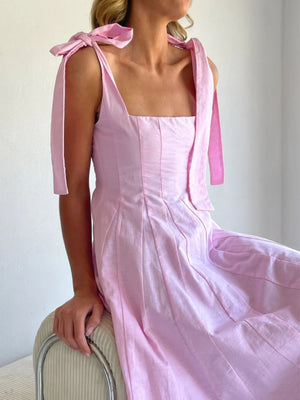 Pink bow-tie shoulder maxi dress with square neckline and pleated skirt.