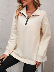 Cream quarter-zip relaxed fit sweatshirt with black zipper detail and ribbed cuffs.