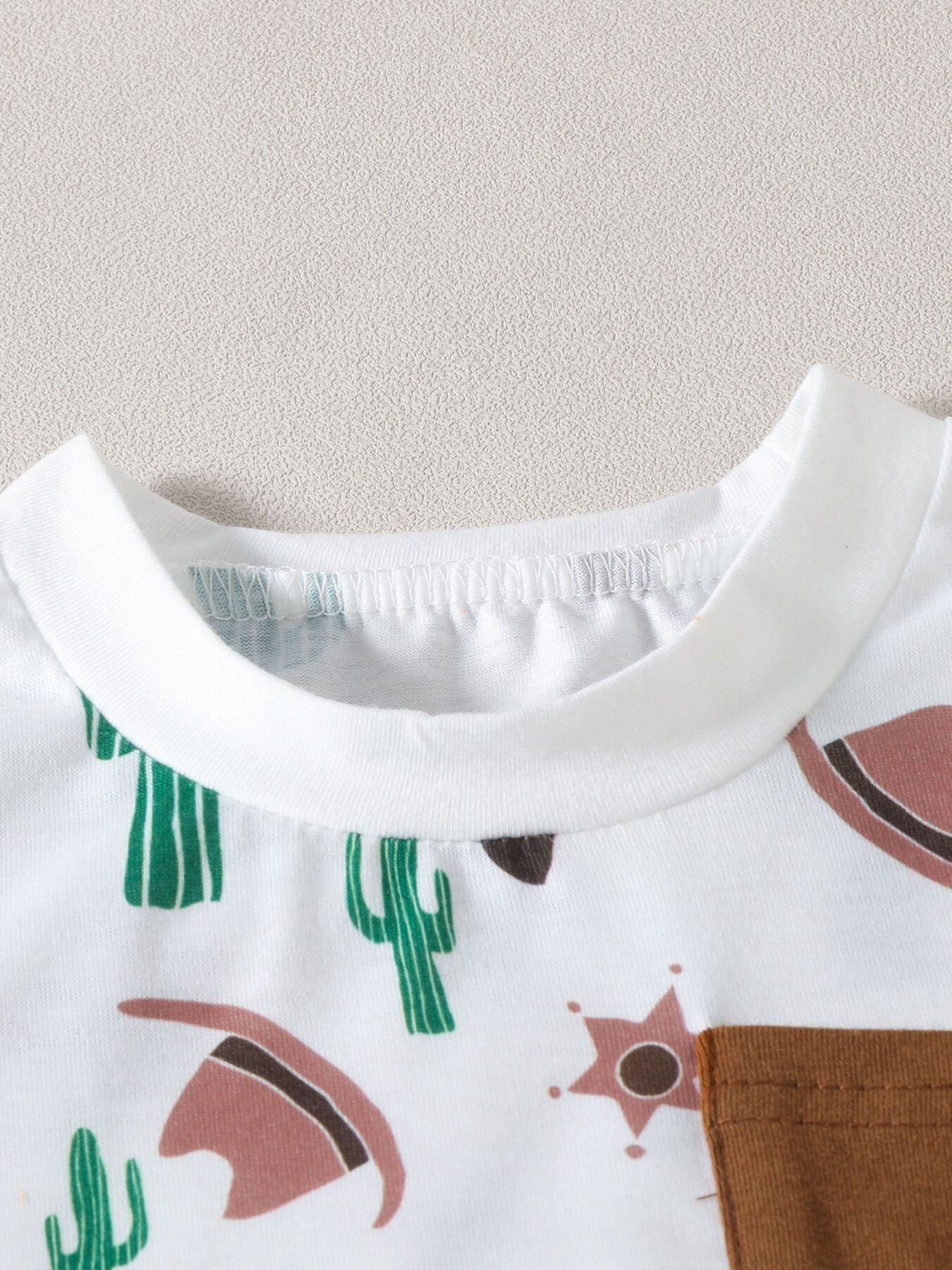 Baby set with cactus and cowboy hat print, white with brown pocket detail.