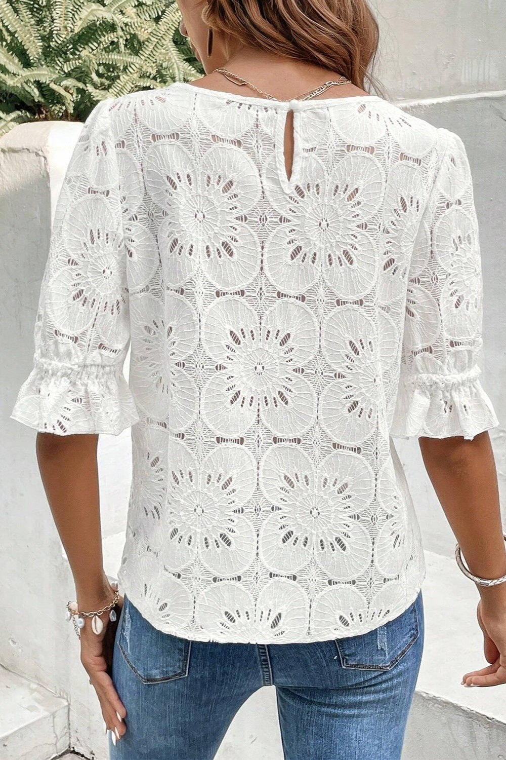White eyelet lace blouse with puff sleeves and ruffled cuffs.