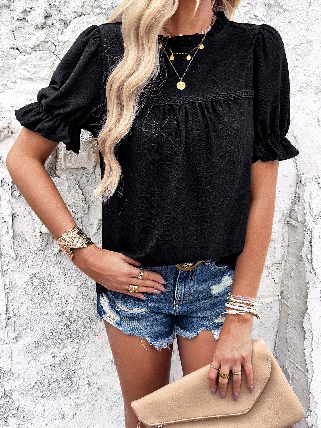 Black eyelet blouse with ruffled puff sleeves and mock neck.