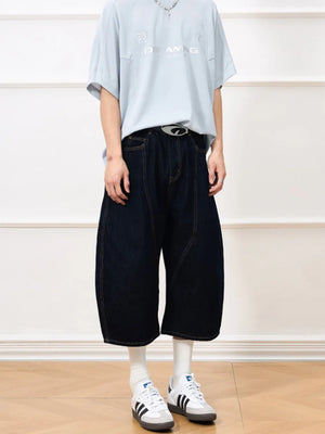 Oversized cropped denim shorts in dark navy cotton with balloon cut and visible stitching.