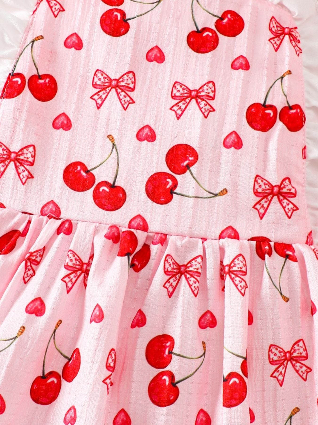 Baby dress in pink cotton with cherry and bow print, featuring ruffle trim.