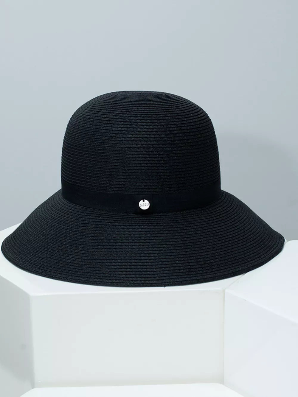 Black straw sun hat with elegant ribbon and silver charm detail.