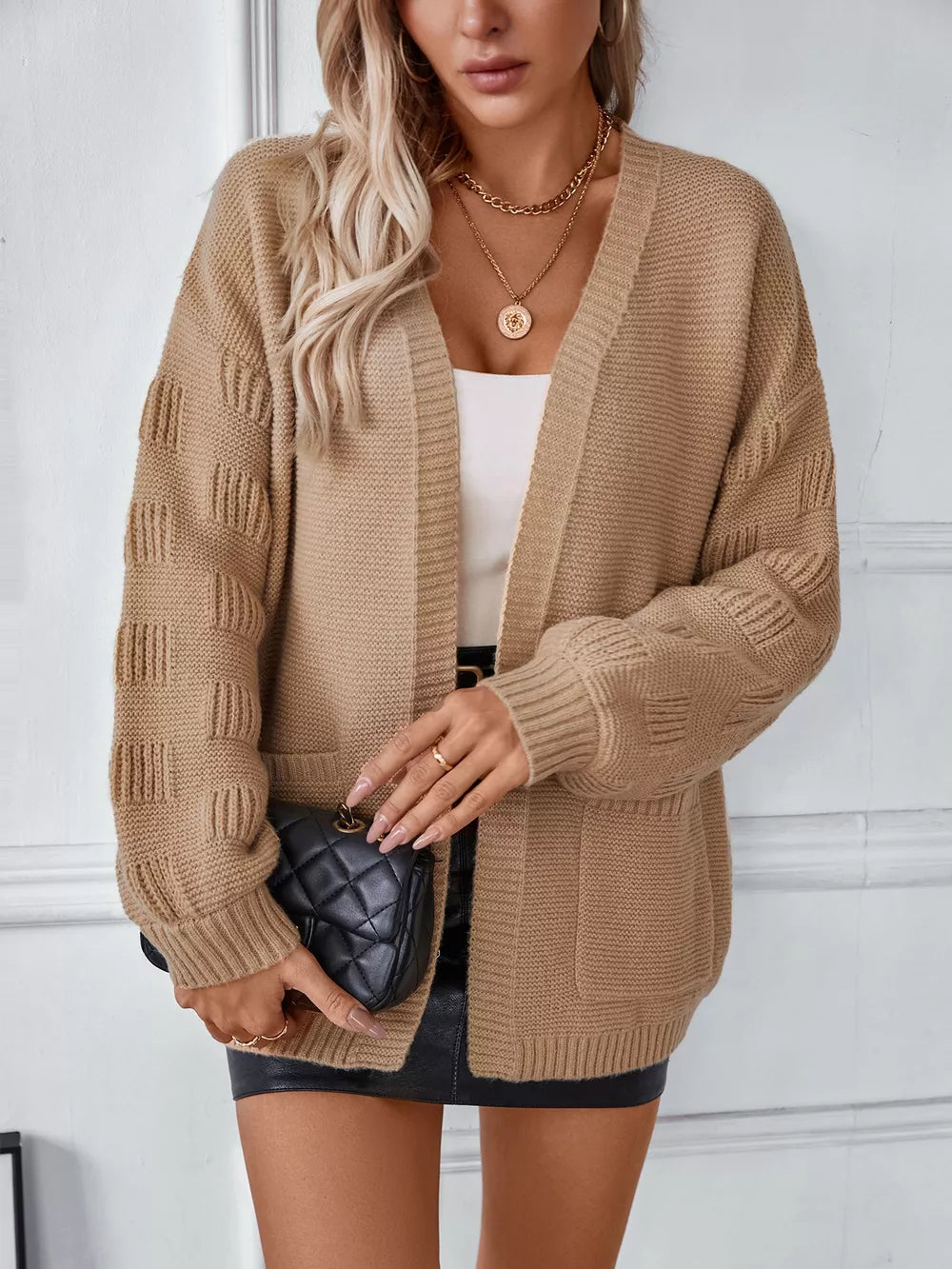 Camel chunky knit open-front cardigan with pockets and textured sleeves.