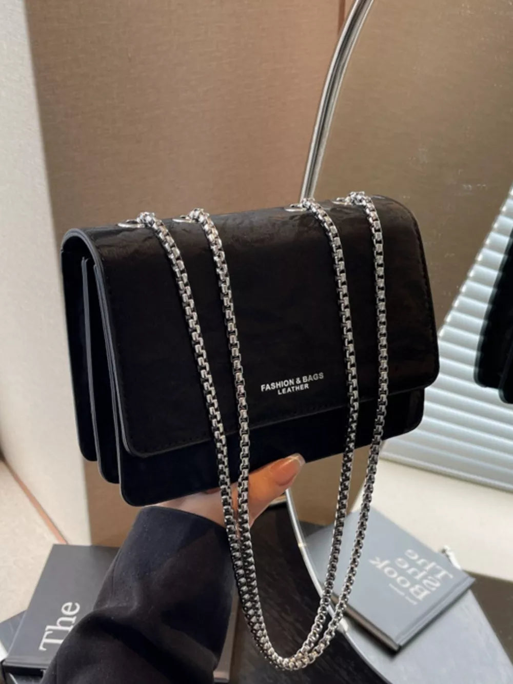 Black crumpled texture mini shoulder bag with silver chain strap and embossed logo.