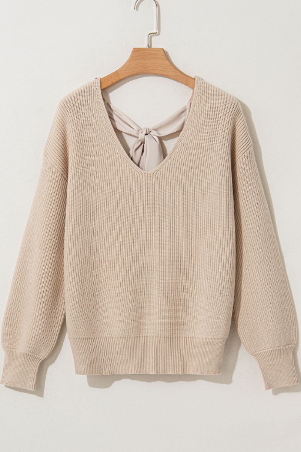Beige ribbed knit sweater with V-neck and back bow detail