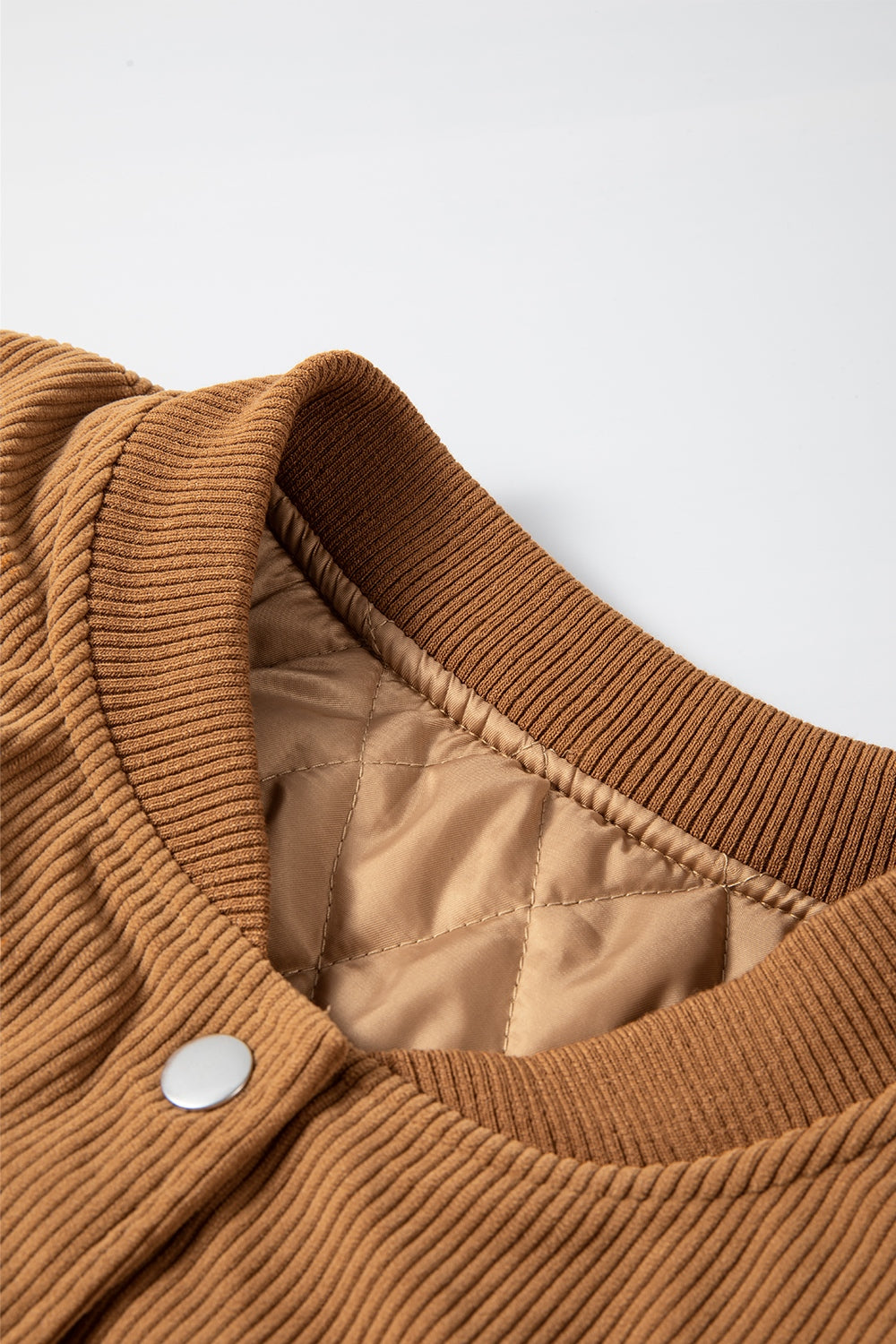 Terracotta corduroy bomber jacket with quilted lining and ribbed collar.