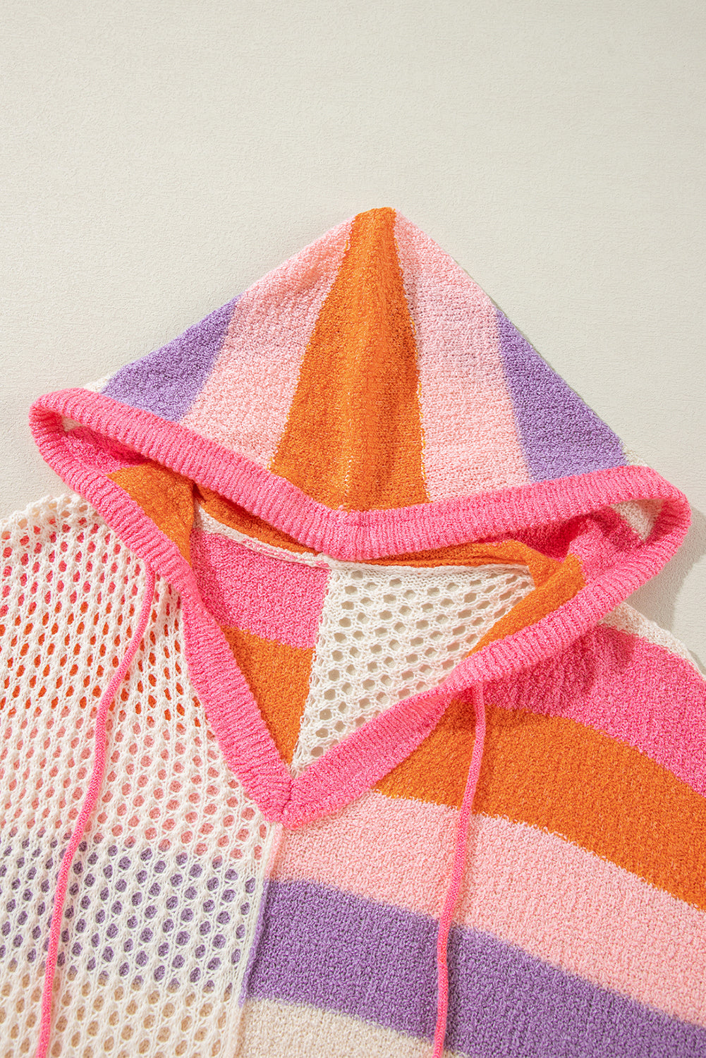 Colorblock knit hoodie with crochet panels and drawstring hood in pink, orange, purple, and beige stripes.