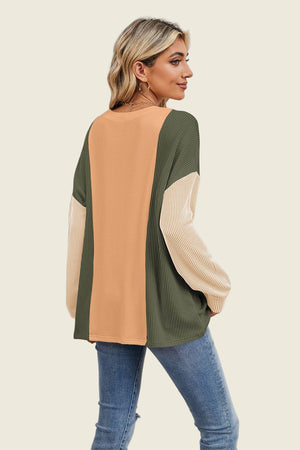 Colorblock waffle knit pullover with tan, dark green, and white sleeves.