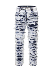 Distressed shredded denim jeans in medium wash with artistic sculptural pattern.