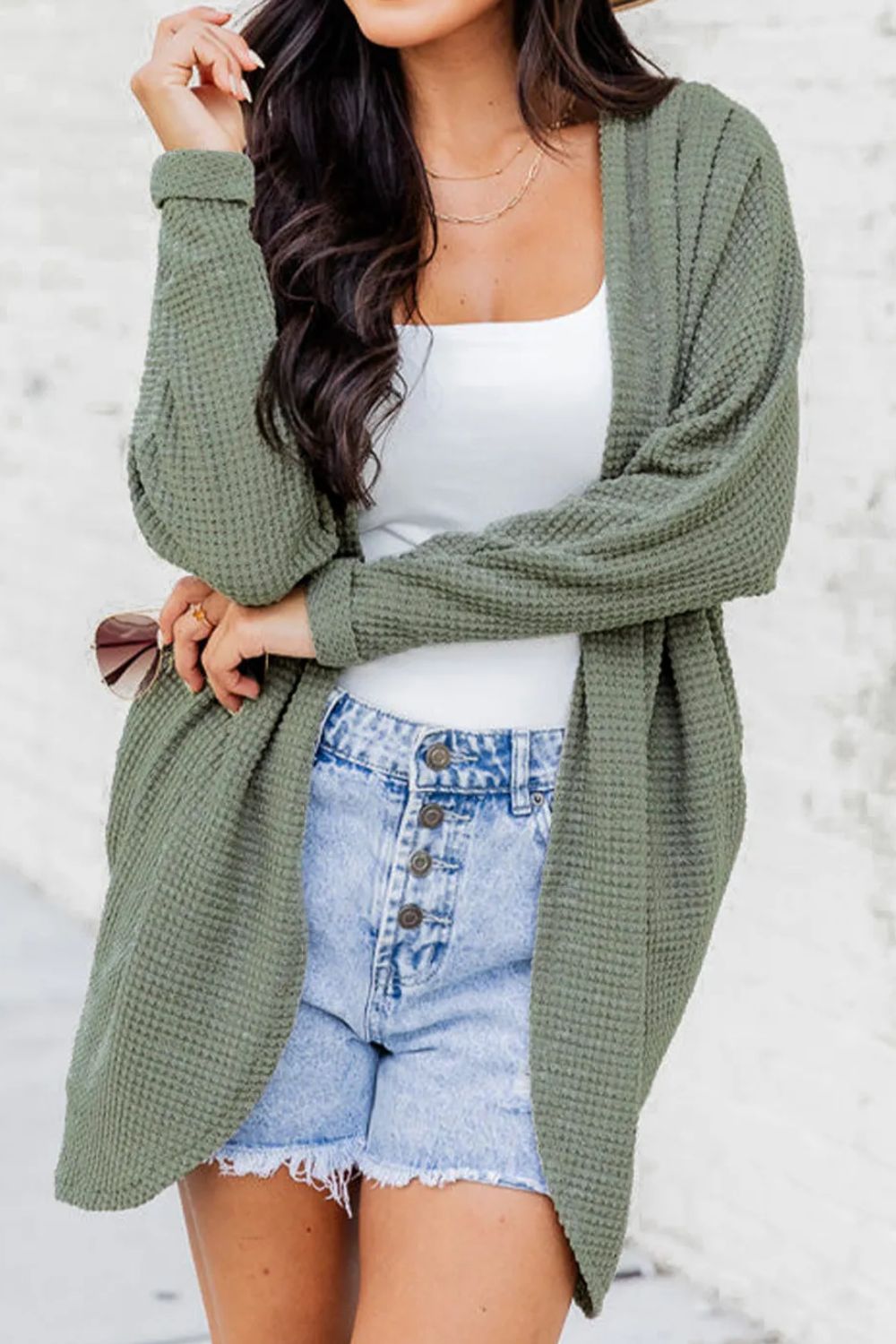 Sage waffle knit open-front duster cardigan with long sleeves, worn over a white tank top and denim shorts.