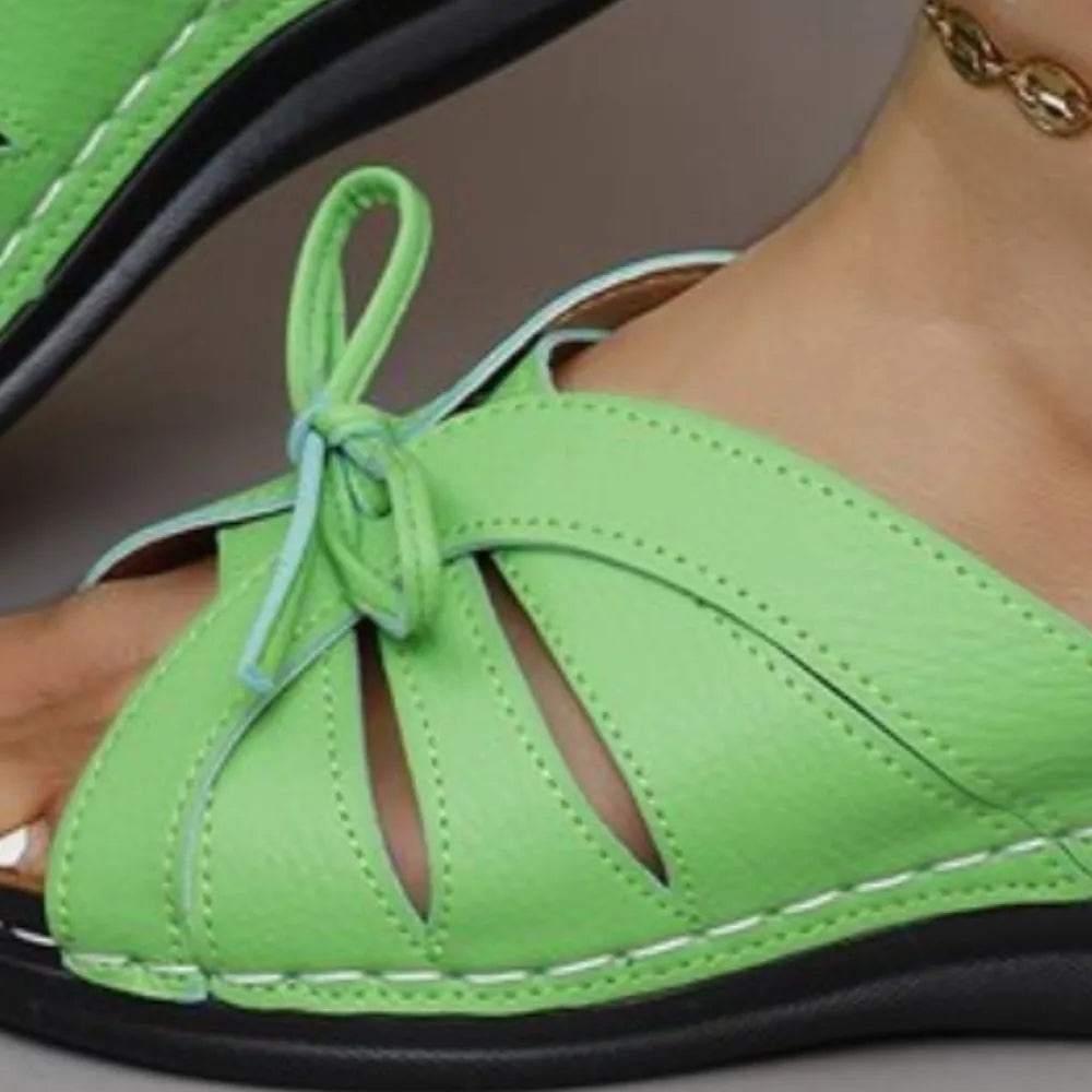 Neon green leather lace-up cutout slides with white stitching and a bow detail.
