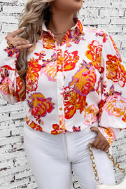 Floral print blouse with blouson sleeves and button front, styled with white pants.