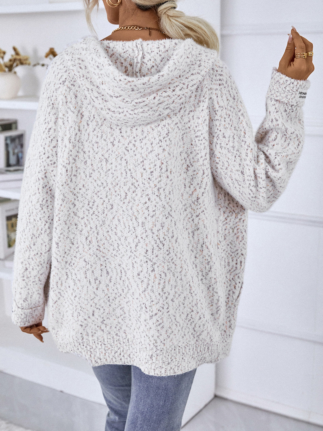Textured knit zip-up hoodie in white with speckles, featuring a logo detail on the sleeve.