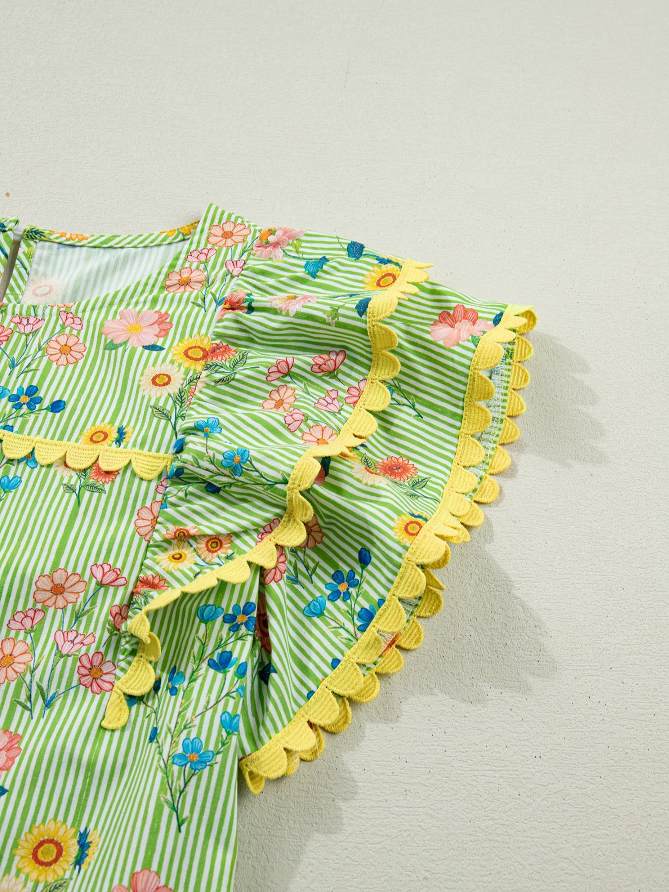 Green striped cotton blouse with floral print, ruffle short sleeves, and yellow scalloped trim.