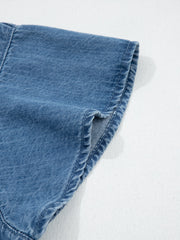 Denim button-up shirt detail showing a rolled sleeve cuff with visible stitching.