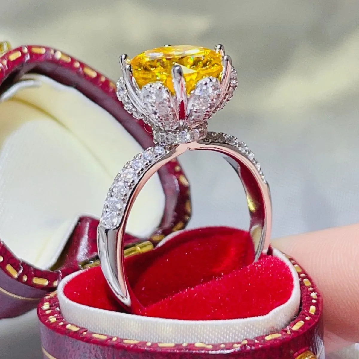 Yellow moissanite solitaire ring with diamond-accented band in a jewelry box.