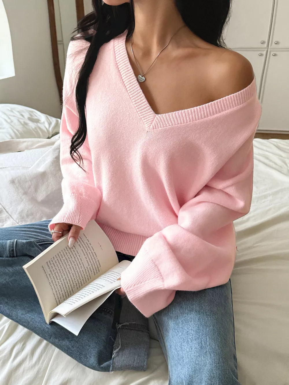 Blush pink V-neck knit sweater with ribbed neckline and cuffs, worn off-shoulder.