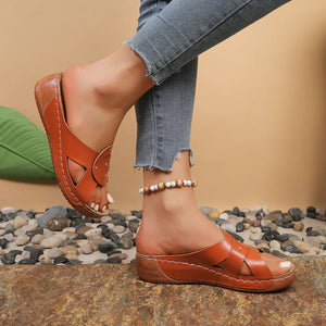 Brown slip-on wedge sandals with riveted detail and crisscross straps.
