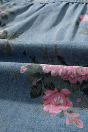 Denim button-up shirt with pink floral print and ruffled detail.