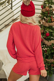 Textured red loungewear set with ribbed shorts and long sleeve top, styled with a pom-pom beanie.