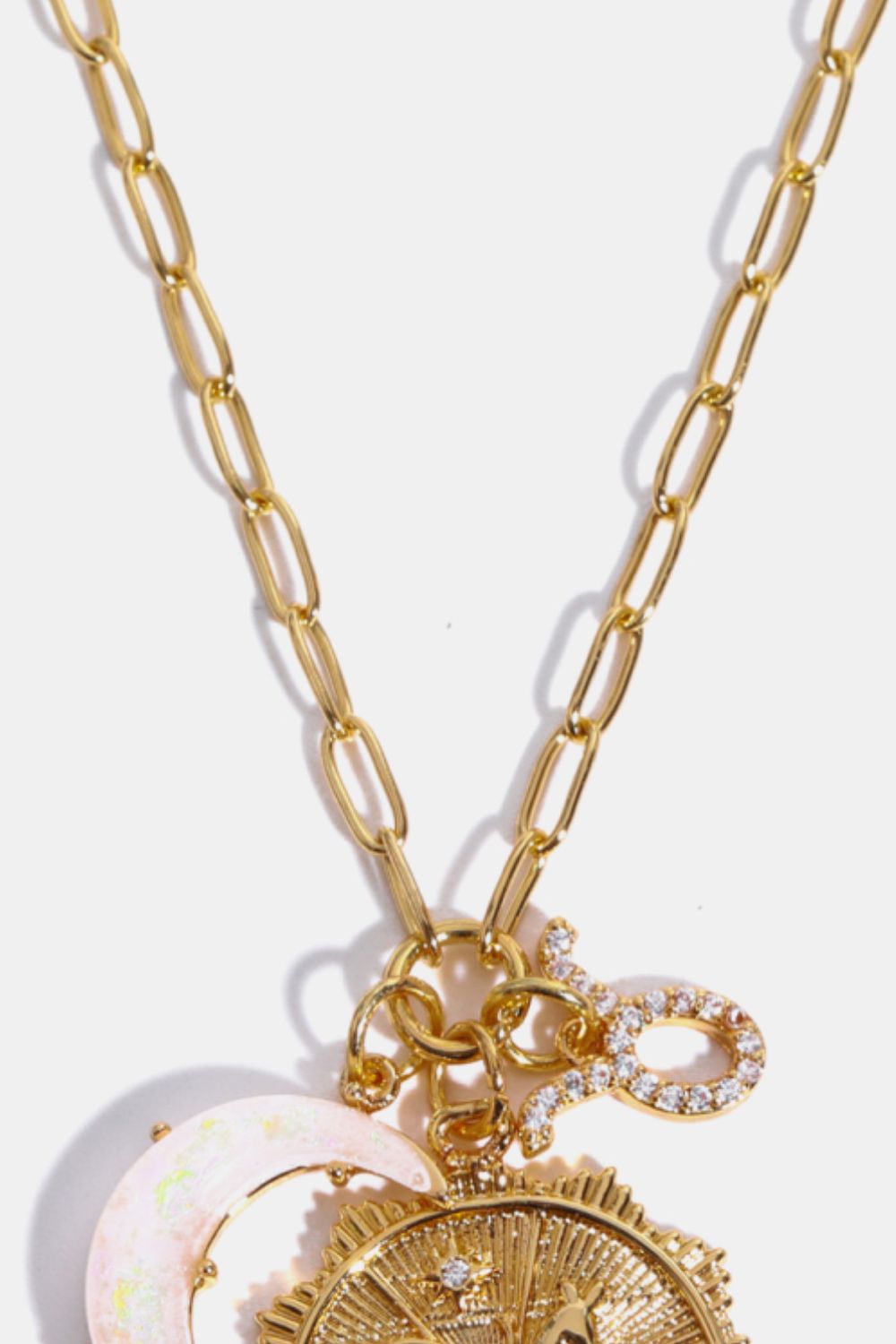 Gold celestial zodiac pendant necklace with moon and sun charms, and a diamond-encrusted zodiac symbol.